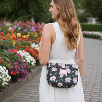 Woman in a white dress with a Minnie Mouse black floral-patterned bag walking through a garden with colorful flowers.