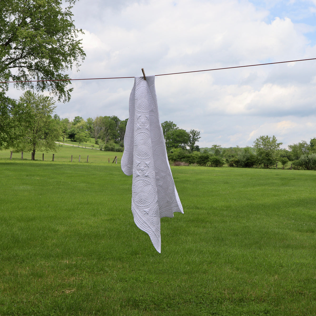 white embroidered baby quilt hanging on a clothes line
