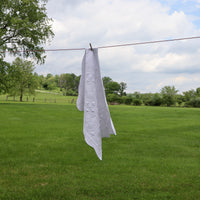 white embroidered baby quilt hanging on a clothes line